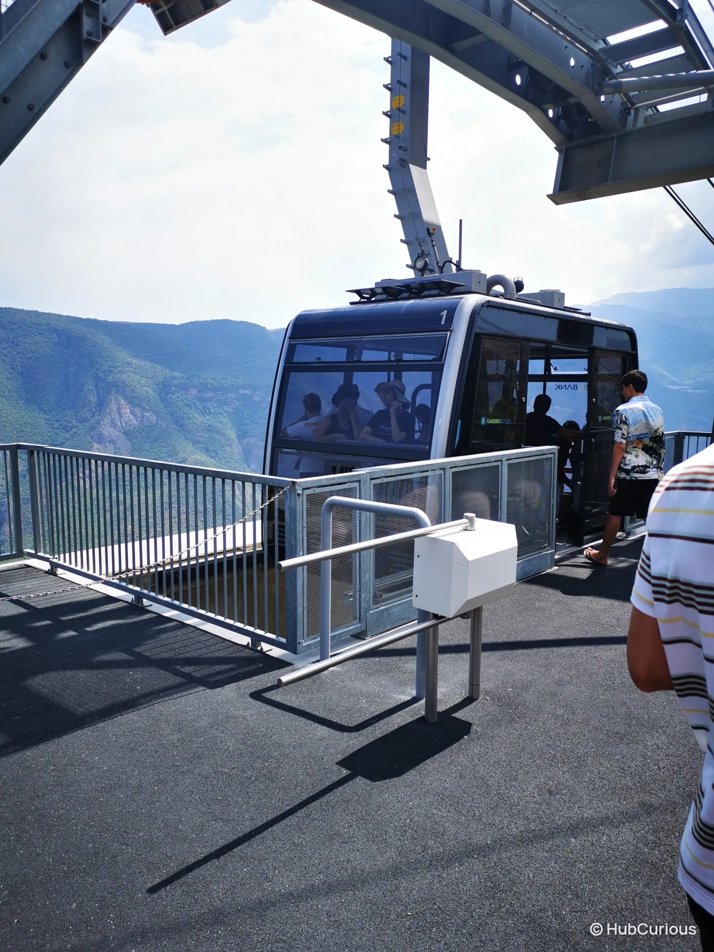 Wings of Tatev cabin waiting at the station platform with passengers boarding and the green Vorotan gorge behind