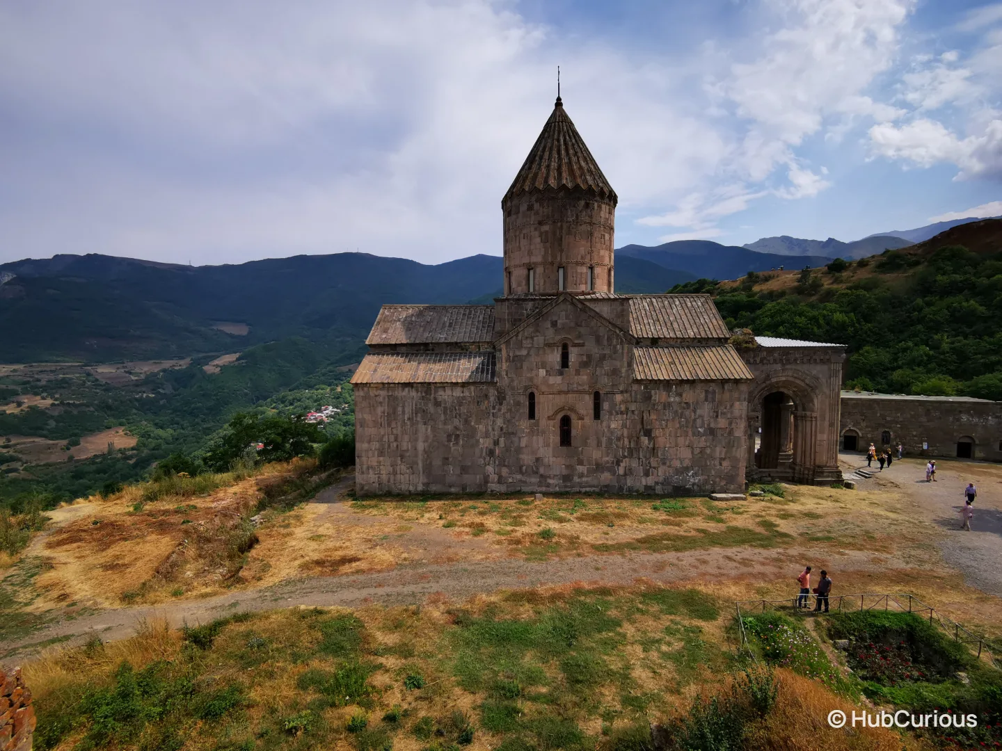 Tatev Monastery church with its conical dome standing on the plateau above the valley, mountains in the distance