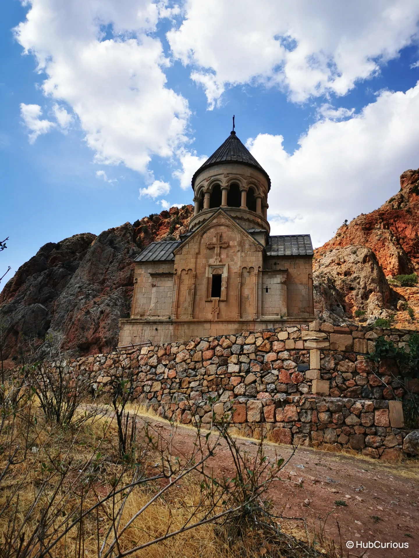 Church at Noravank on its stone terrace with the red cliffs of the Amaghu gorge rising behind it
